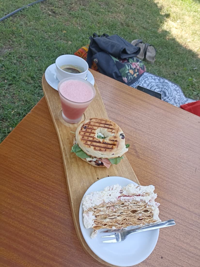 Tabla con sándwich, jugo y milhojas sobre la mesa de madera